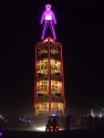 Burning Man in all his glory atop the obelisk of flags of all the world.
