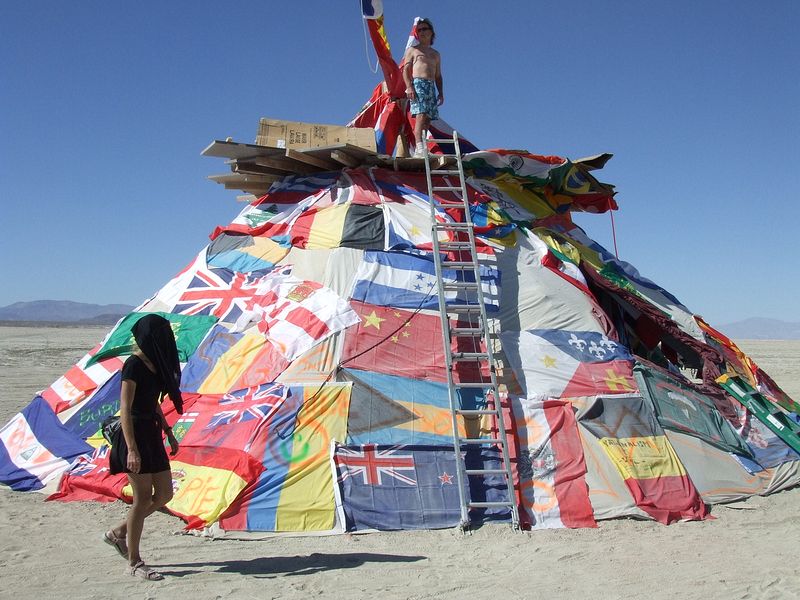 TRASH FENCE by Bob Noxious. A large American Indian tipi is adorned with every nations flag.
